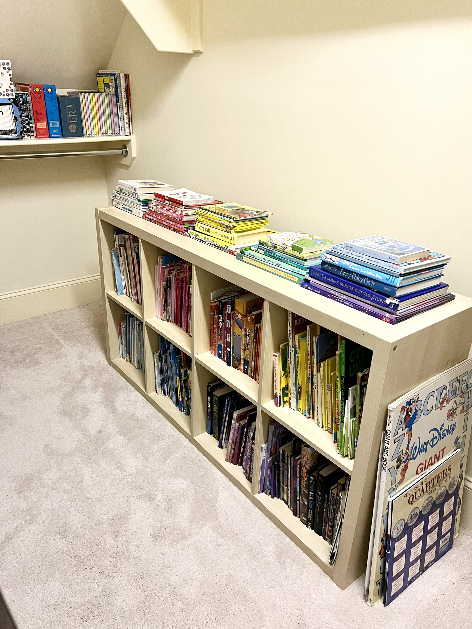 Books and board games organized by color on white shelves